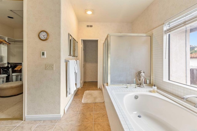 bathroom with tile patterned floors, a shower stall, a bath, a walk in closet, and visible vents