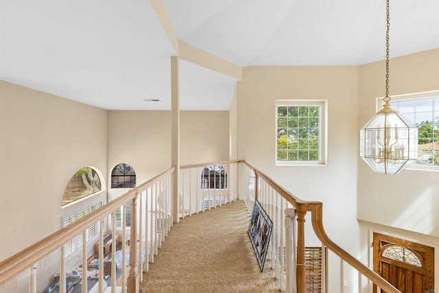 hallway featuring a chandelier, an upstairs landing, and carpet floors