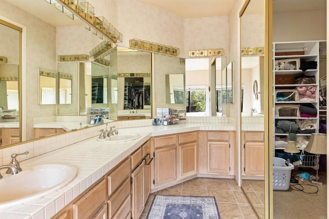 full bath featuring a walk in closet, tile patterned floors, double vanity, and a sink