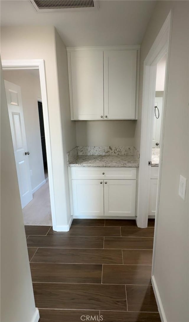 kitchen featuring wood finish floors, visible vents, white cabinetry, and baseboards