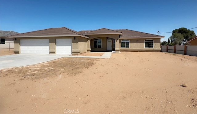 ranch-style house featuring stucco siding, a tiled roof, fence, concrete driveway, and an attached garage