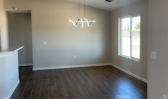 unfurnished dining area with dark wood finished floors, baseboards, and plenty of natural light
