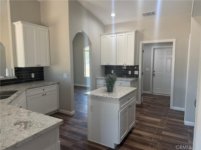 17995 Seaforth St, Hesperia, CA 92345 - kitchen with arched walkways, dark wood-type flooring, white cabinets, tasteful backsplash, and light stone countertops