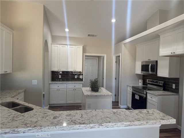 17995 Seaforth St, Hesperia, CA 92345 - kitchen featuring stainless steel appliances, decorative backsplash, white cabinetry, arched walkways, and light stone counters