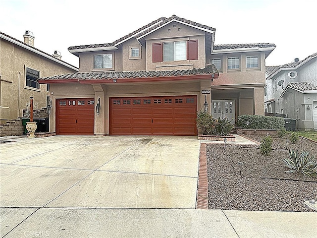 view of front of property featuring a garage, a tiled roof, driveway, and stucco siding
