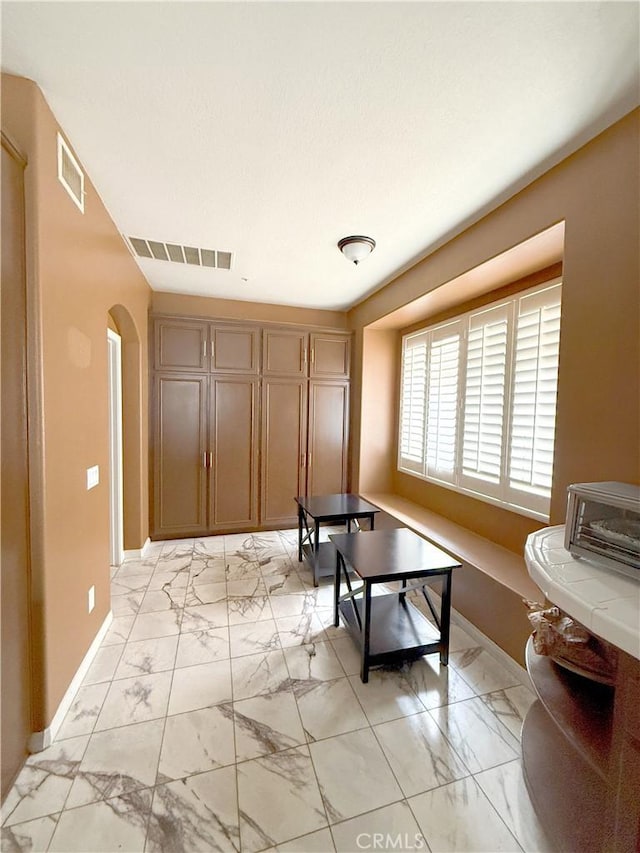 interior space featuring baseboards, marble finish floor, and visible vents