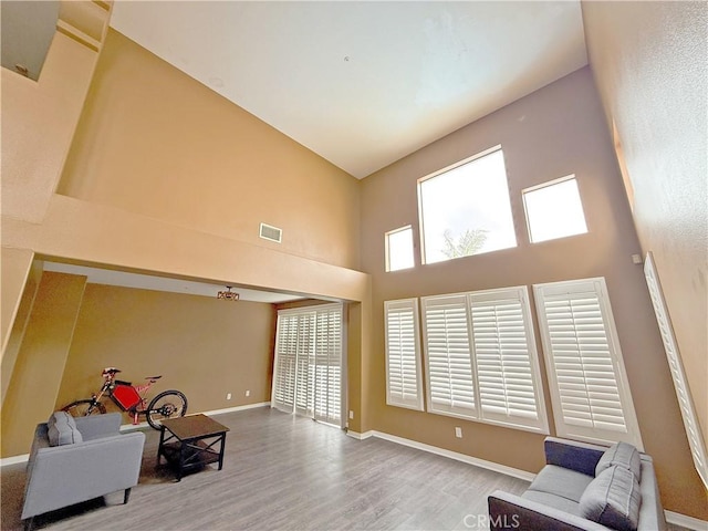 sitting room featuring visible vents, a high ceiling, baseboards, and wood finished floors