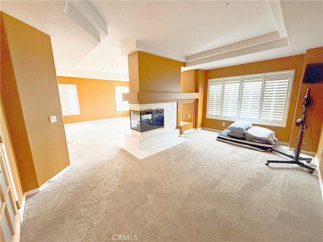 unfurnished living room featuring a raised ceiling, baseboards, a fireplace, and carpet flooring