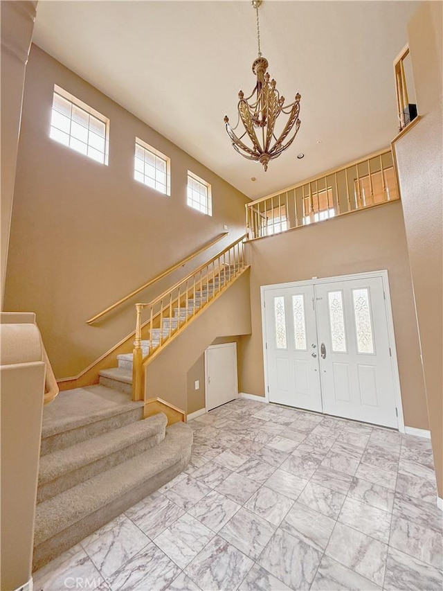 foyer featuring baseboards, stairs, a towering ceiling, and a notable chandelier