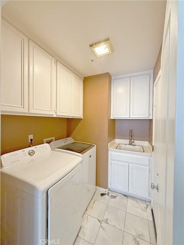 washroom with washing machine and clothes dryer, cabinet space, a sink, baseboards, and marble finish floor