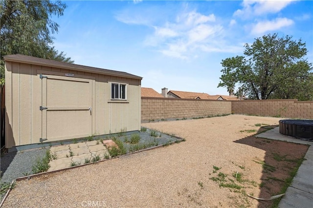 view of yard with an outdoor structure, a fenced backyard, and a storage shed