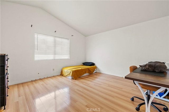 bedroom featuring baseboards, light wood-style flooring, and lofted ceiling
