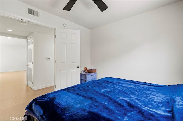bedroom with a ceiling fan, baseboards, wood finished floors, vaulted ceiling, and visible vents