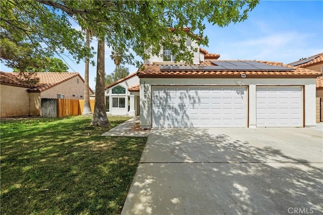 mediterranean / spanish-style home featuring a tile roof, stucco siding, a front yard, solar panels, and driveway