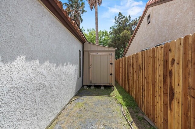1555 Berkshire Dr, Palmdale, CA 93551 - view of side of home featuring fence, a storage unit, an outbuilding, and stucco siding