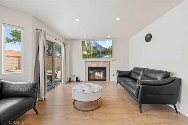 living area featuring recessed lighting, a glass covered fireplace, and light wood finished floors