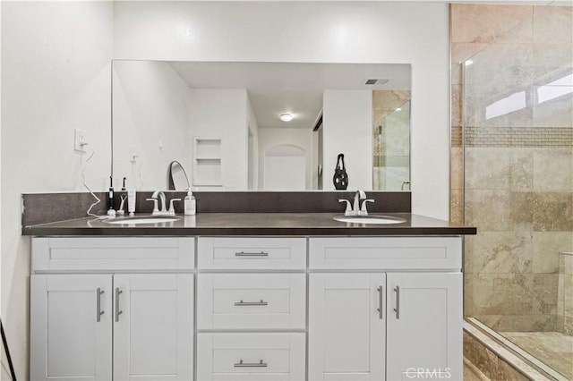bathroom with a sink, a stall shower, and double vanity
