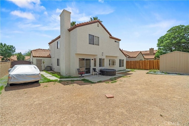 back of house featuring a chimney, a tile roof, a patio area, a fenced backyard, and stucco siding