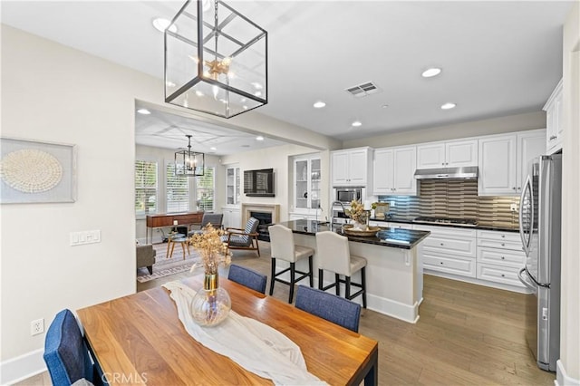 dining area with visible vents, a fireplace, wood finished floors, an inviting chandelier, and recessed lighting