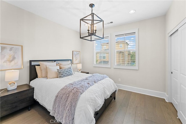 bedroom with an inviting chandelier, visible vents, wood finished floors, baseboards, and recessed lighting