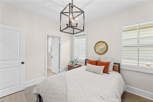 bedroom featuring baseboards, an inviting chandelier, and wood finished floors