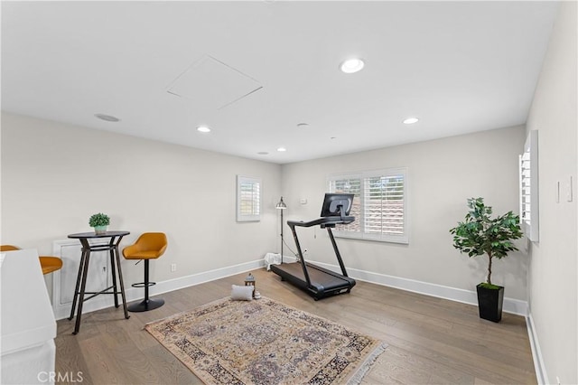 workout area featuring baseboards, recessed lighting, and wood finished floors