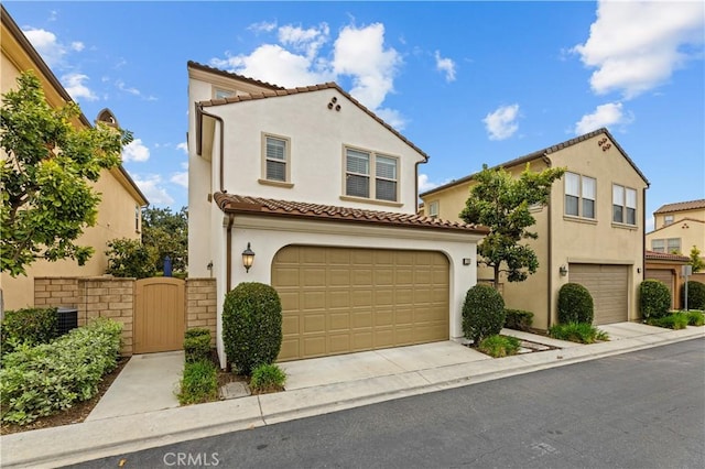 mediterranean / spanish house with a tiled roof, a garage, driveway, and stucco siding