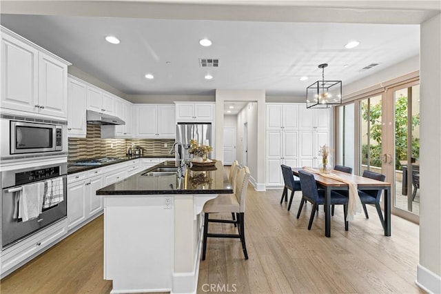 kitchen featuring white cabinets, appliances with stainless steel finishes, a sink, recessed lighting, and under cabinet range hood