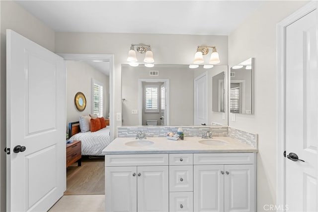 ensuite bathroom featuring a sink, tasteful backsplash, ensuite bath, and double vanity