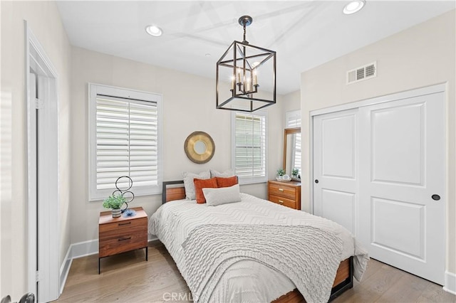 bedroom featuring light wood-style floors, a chandelier, recessed lighting, visible vents, and a closet