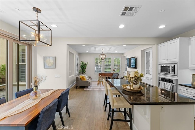 kitchen with visible vents, light wood-type flooring, white cabinets, a chandelier, and stainless steel appliances