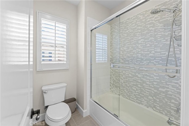 bathroom featuring toilet, baseboards, tile patterned flooring, and bath / shower combo with glass door