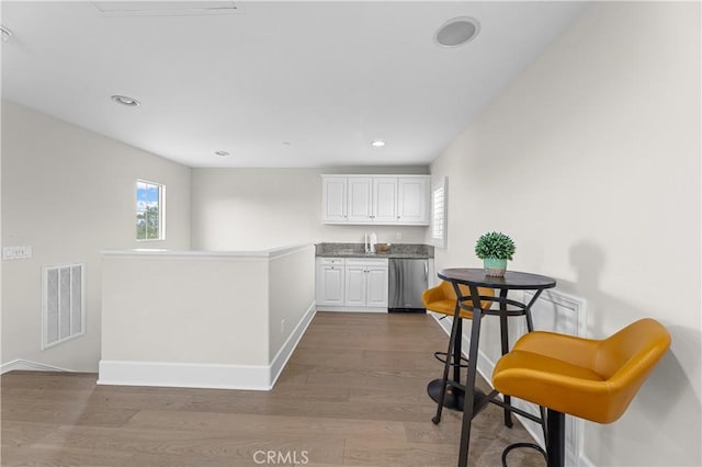 kitchen with visible vents, dishwasher, baseboards, white cabinetry, and dark wood-type flooring