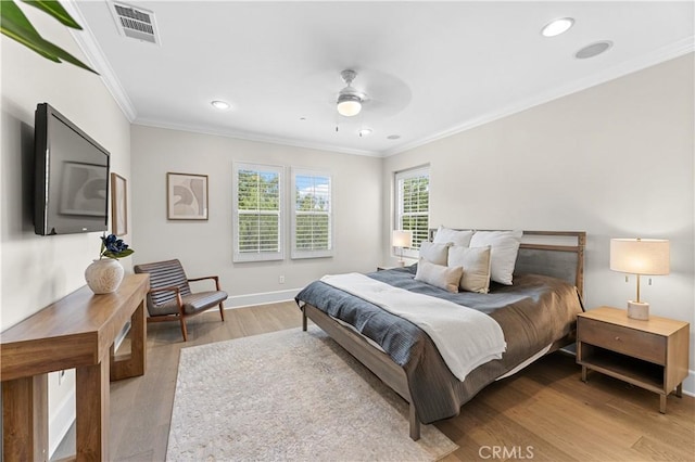 bedroom featuring baseboards, visible vents, ornamental molding, and light wood finished floors