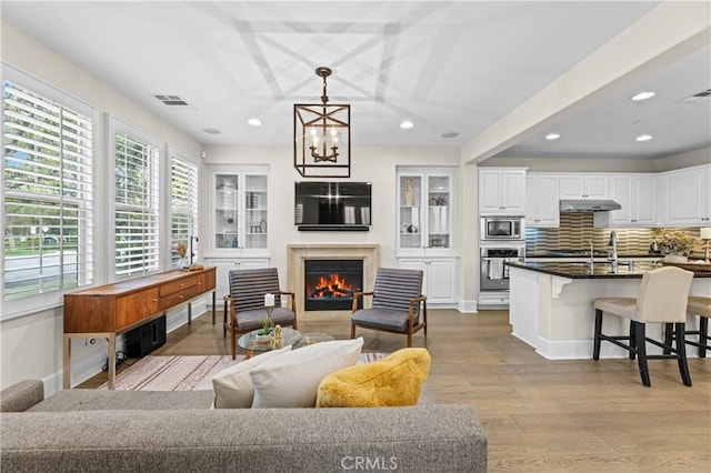 living area featuring visible vents, recessed lighting, wood finished floors, and a notable chandelier
