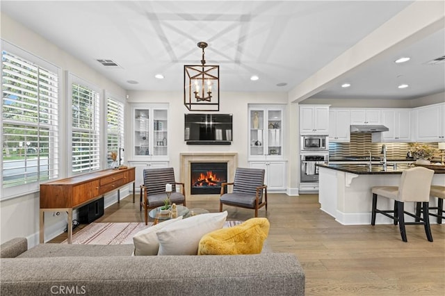 129 Pathway, Irvine, CA 92618 - living area featuring wood finished floors, recessed lighting, a chandelier, a warm lit fireplace, and baseboards