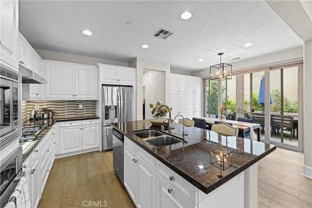 kitchen with a sink, stainless steel appliances, recessed lighting, and an island with sink