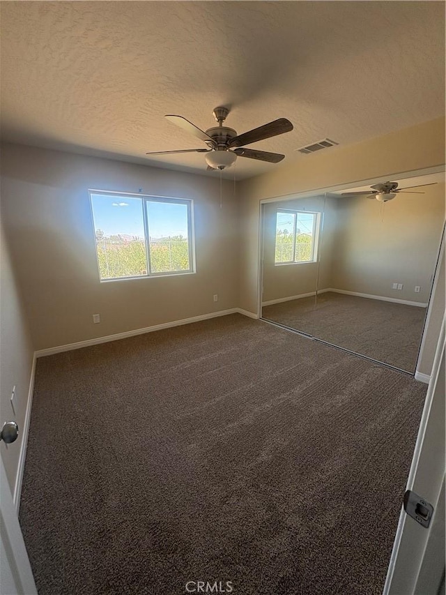 unfurnished bedroom featuring baseboards, carpet, a textured ceiling, and visible vents