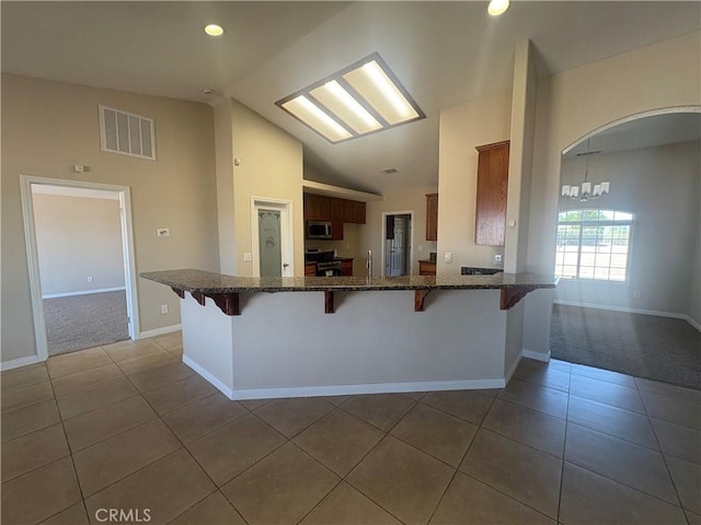 kitchen with a kitchen bar, visible vents, appliances with stainless steel finishes, tile patterned floors, and a peninsula