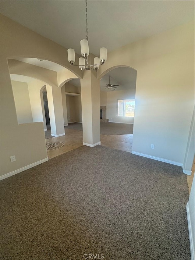 unfurnished dining area featuring arched walkways, light colored carpet, light tile patterned floors, and ceiling fan with notable chandelier
