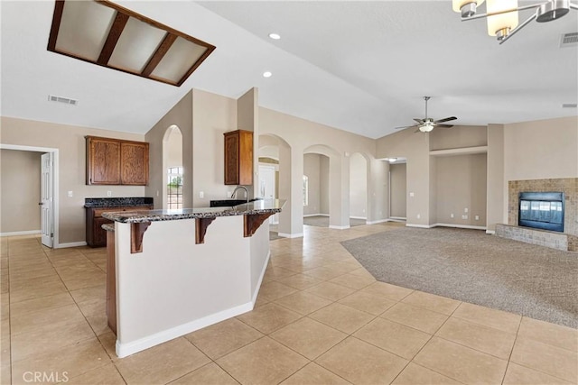 11569 Arroyo Ave, Hesperia, CA 92345 - kitchen featuring light tile patterned floors, vaulted ceiling, a breakfast bar area, arched walkways, and a ceiling fan