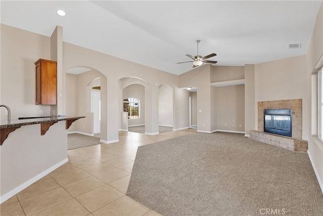 11569 Arroyo Ave, Hesperia, CA 92345 - unfurnished living room featuring a ceiling fan, lofted ceiling, light tile patterned flooring, arched walkways, and a glass covered fireplace