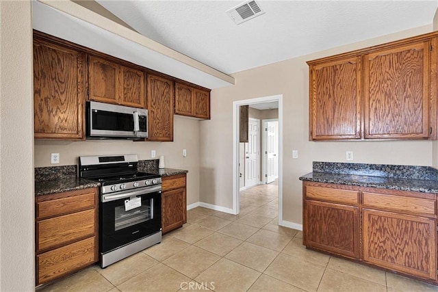11569 Arroyo Ave, Hesperia, CA 92345 - kitchen with stainless steel appliances, baseboards, light tile patterned flooring, dark stone countertops, and brown cabinets