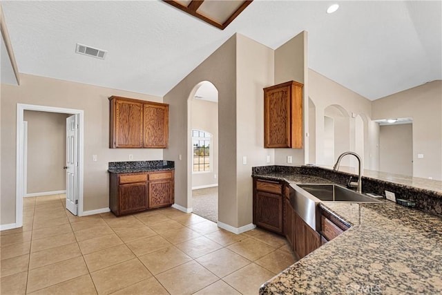 11569 Arroyo Ave, Hesperia, CA 92345 - kitchen featuring vaulted ceiling, a sink, baseboards, arched walkways, and light tile patterned floors