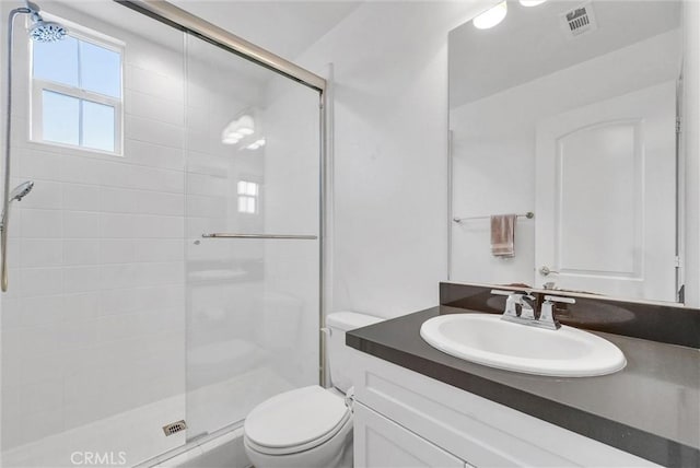bathroom with visible vents, toilet, a shower stall, and vanity