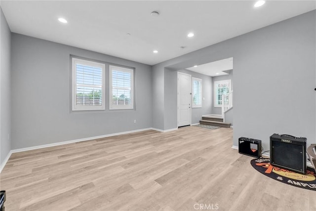 unfurnished living room featuring baseboards, recessed lighting, stairs, and light wood finished floors