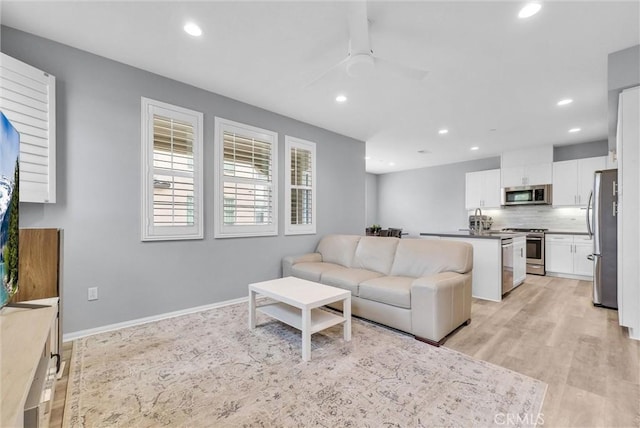living room featuring recessed lighting, a ceiling fan, baseboards, and light wood-type flooring