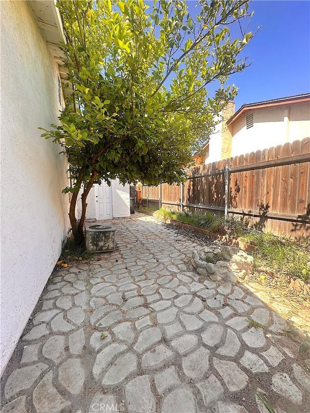 view of patio / terrace featuring an outdoor structure, fence, and a shed