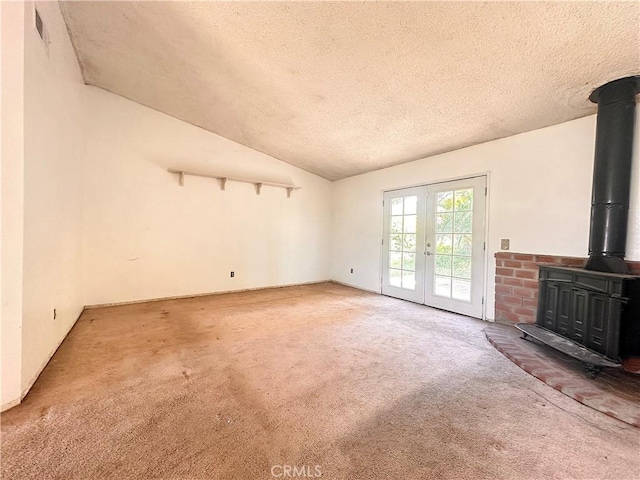 unfurnished living room with french doors, carpet floors, a wood stove, and a textured ceiling