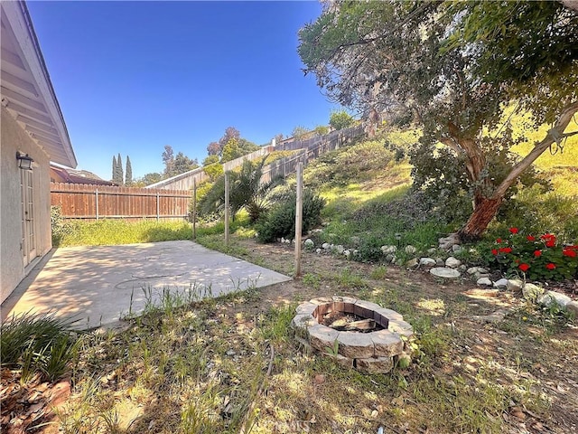 view of yard with a fenced backyard, a fire pit, and a patio area